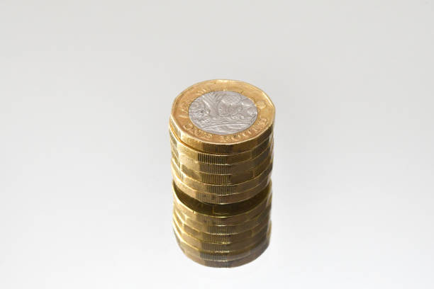 Close up of a column of one pound coins on as mirror surface isolated on a plain white background.  No people. copy space.