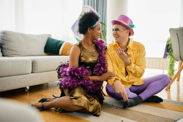 heureux amis multiraciaux en costumes de carnaval qui parlent tout en célébrant mardi gras à la maison. - parade of homes photos et images de collection