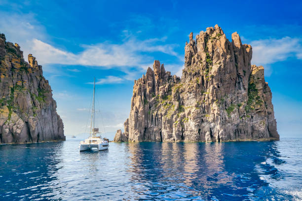 la roca de 79 metros de altura scoglio spinazzola con la isla de basiluzzo al noreste de panarea en sicilia en italia - recreational boat fotos fotografías e imágenes de stock