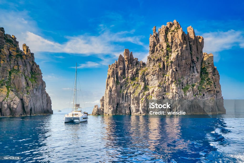 The 79 meter high rock Scoglio Spinazzola with the island of Basiluzzo northeast of Panarea in Sicily in Italy Sailboat Stock Photo