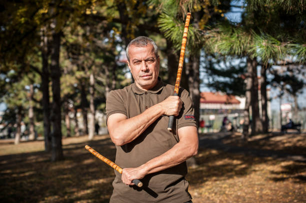 istock Escrima and kapap instructor demonstrates sticks fighting techniques in park 1367528463