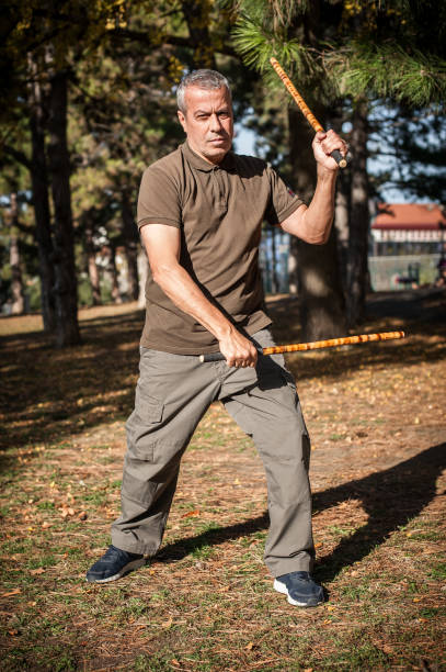 istock Escrima and kapap instructor demonstrates sticks fighting techniques in park 1367528521