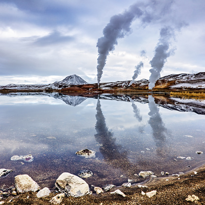 Power generation in the Bjarnarflag geothermal area of northern Iceland. Mirror reflection in the blue lake, with the Namfjoll mountain and steam plumes.
