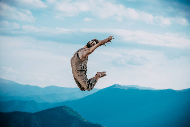 Profile view of a male urban dancer practicing some dance moves and jumping outdoors