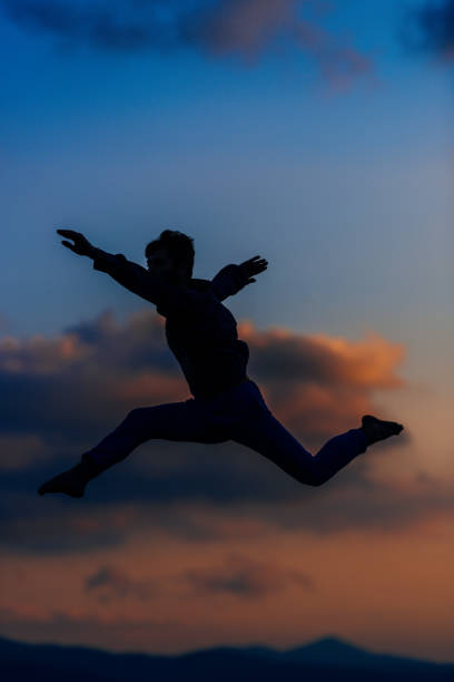 istock Awesome dancer is jumping very high in the sunset sky 1367531641