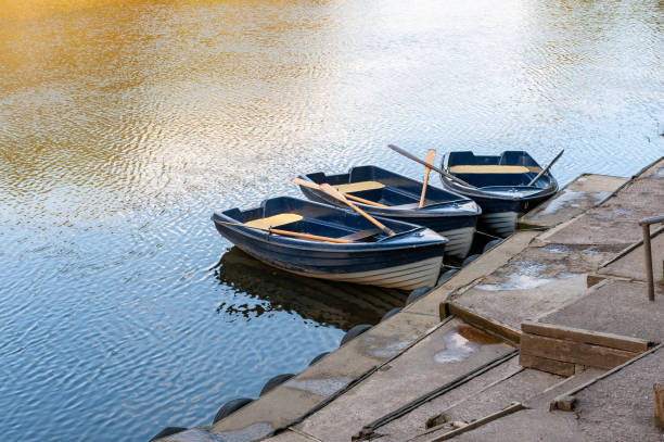 istock Three blue and white rowing boats moored on a tranquil river on a sunny day. 1367532599