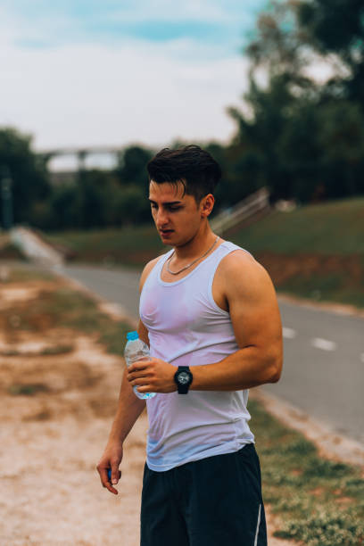 istock Jogger man holding water bottle while resting from running 1367532617