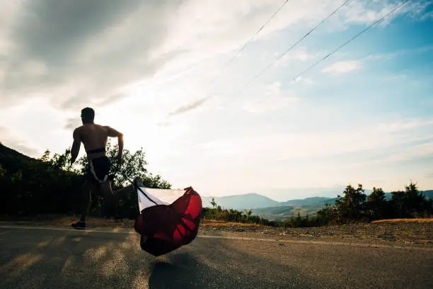 Photo of gym man jogging with resistance parachute on mountain road