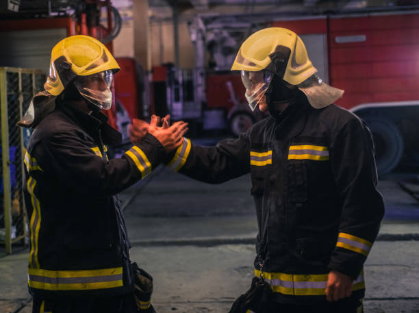 istock Portrait of two young firemen in uniform standing inside the fire station 1367534624