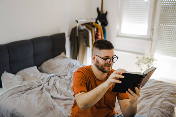 istock Young man lying on bed in his room and studying 1367535187