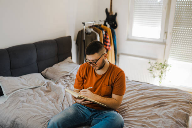 istock Young man lying on bed in his room and studying 1367536007