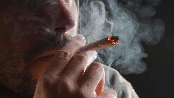 Man smoking a marijuana joint Man smoking a marijuana weed joint, inhaling cannabis smoke. marijuana stock pictures, royalty-free photos & images