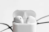 Wireless ear buds in glossy white plastic case on white background.