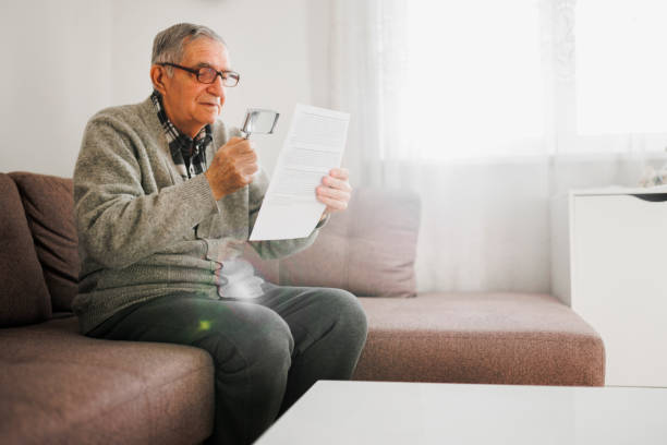 istock Senior man holding an magnifying glass he uses to help him read because he suffers from Wet Macular Degeneration. 1367538549