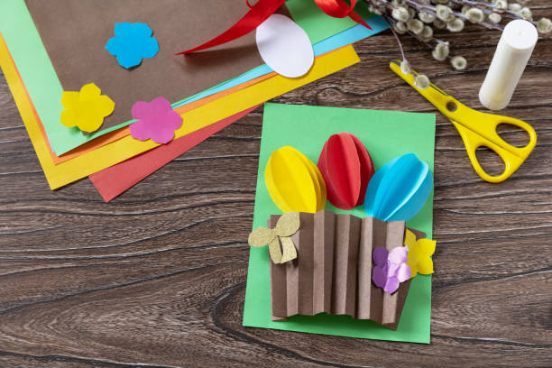 istock Easter congratulation card with basket easter eggs on wooden table. Handmade. Project of childrens creativity, handicrafts, crafts for kids. 1367542329