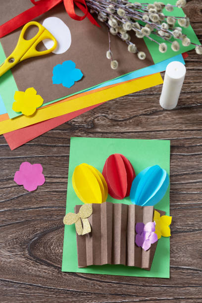 istock Easter congratulation card with basket easter eggs on wooden table. Handmade. Project of childrens creativity, handicrafts, crafts for kids. 1367542330