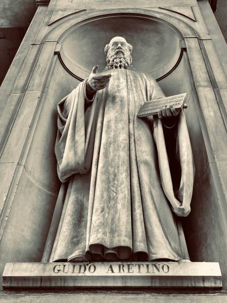 guido aretino (c. 991-1033) - a life size marble sculpture of the italian music theorist and pedagogue of medieval music, (by lornezo nencini - 1837) is housed in one of 28 niches of the colonnade of the uffizi gallery in florence, tuscany, italy. touring the renaissance architecture and sculptures of the piazzale degli uffizi, just oustide the uffizi gallery, florence, tuscany, italy - august 2021 historical museum stock pictures, royalty-free photos & images