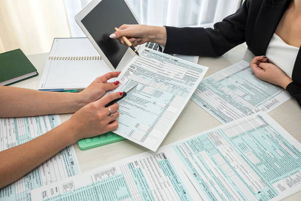 istock two beautiful office ladies sitting at a table and describing tax forms 1040. 1367545677