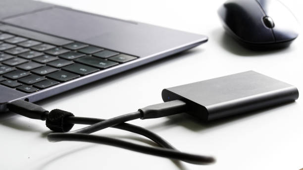 istock An external portable SSD drive connected to a laptop on a white background next to a computer mouse. Portable Solid State Drive. The concept of modern gadgets and the use of an SSD disk 1367546830