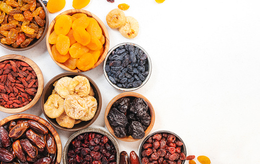 Natural sun dried fruits assortment in bowls on white background. Healthy wholesome snacks. Copy space