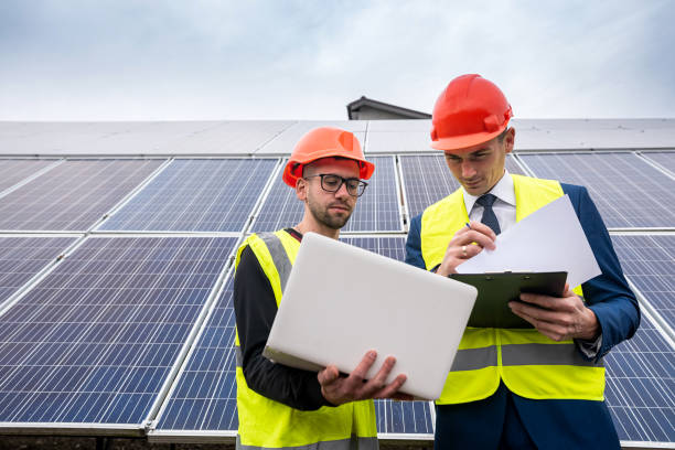 handsome young guys in hard hats with documents stand near the newly installed panels. handsome young guys in hard hats with documents stand near the newly installed panels. Green electricity concept sustainable business stock pictures, royalty-free photos & images