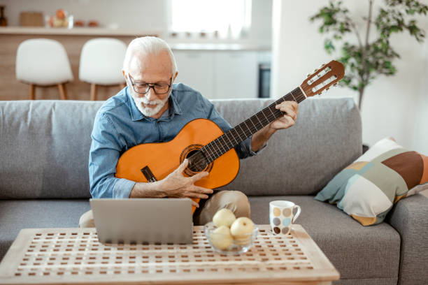 istock Bearded Senior Man Playing Guitar and Watching Online Lessons 1367548745