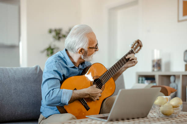 istock Bearded Senior Man Playing Guitar and Watching Online Lessons 1367548796