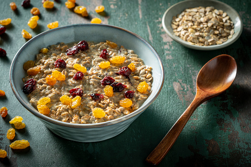 Overnight oats vegan recipe breakfast bowl homemade, including ingredients as rolled oats, soy milk, peanut butter, ground flaxseed, banana, maple syrup dried cranberries and raisins.