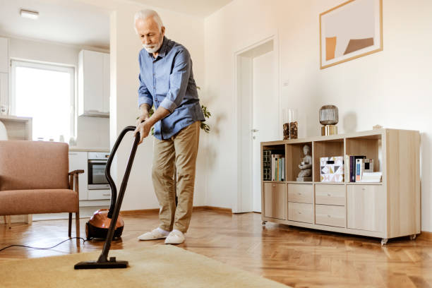 istock Senior Man Cleaning Carpet With Vacuum Cleaner 1367549680