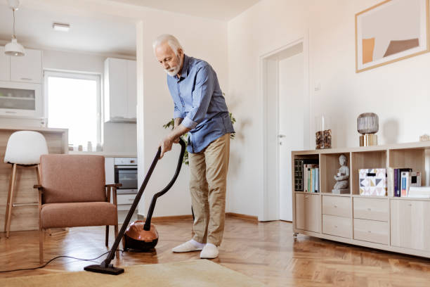 istock Senior Man Cleaning Carpet With Vacuum Cleaner 1367549688