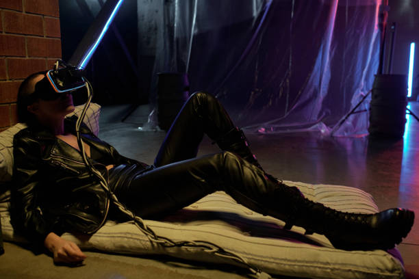 istock Young cyberpunk female in black leather clothes and vr headset 1367549852