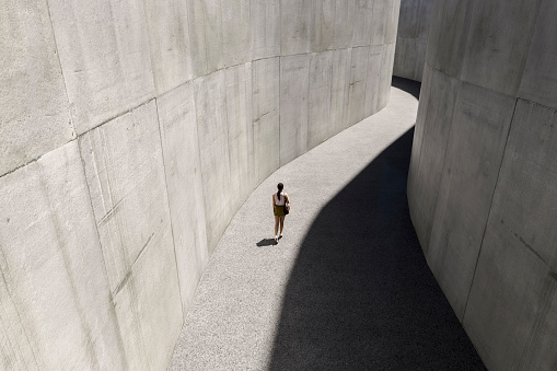 Woman walking in concrete corridor - 3D generated image.