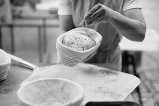 istock Baker woman sprinkles flour on the shaped loaves, rustic style, bread before baking, rustic whole grain bread. 1367550058