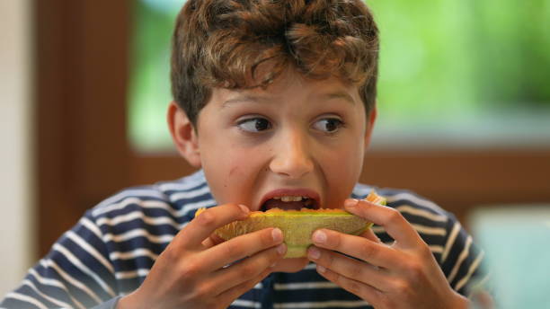 istock Young boy eating melon fruit. Child eats healthy food 1367551133
