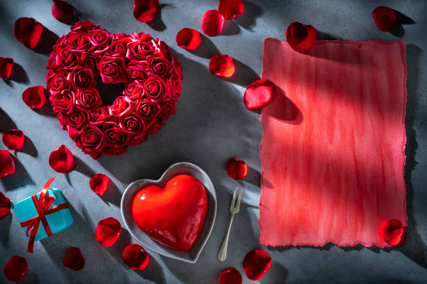 istock Valentines red rose flower petals and heart shape cake on gray copy space 1367551256
