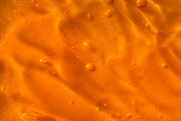 textura de gel amarelo transparente com bolhas de ar e ondas no fundo laranja - vitamin e fotos - fotografias e filmes do acervo