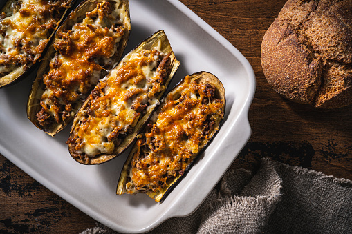 Stuffed Eggplants with minced meat recipe italian Aubergine Parmigiana or Eggplant parmesan on rustic wood table in an oven tray