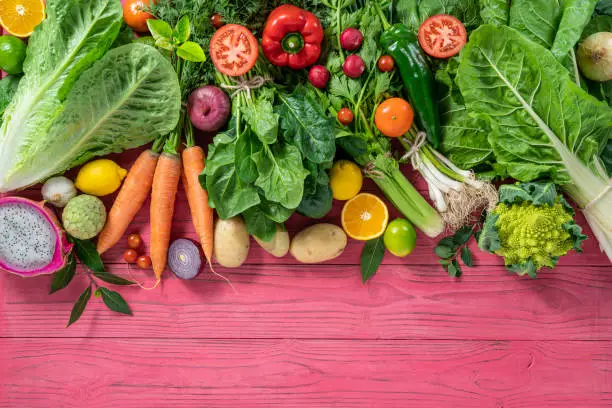 Photo of Fruits and vegetables assorted on pink wooden background