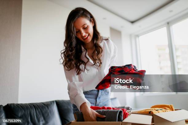 Woman Sorting Clothing And Packing Donation Box Stock Photo - Download Image Now - Decluttering, Closet, Domestic Life
