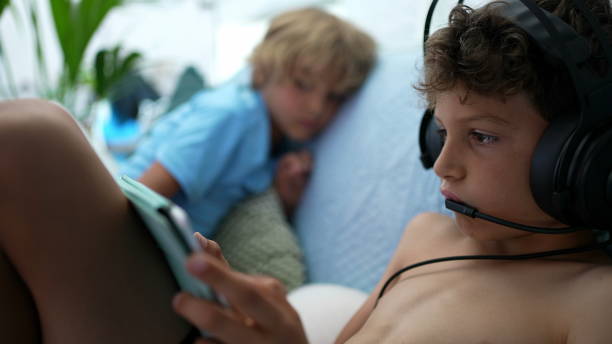 istock younger brother watching sibling play game on tablet device 1367553377