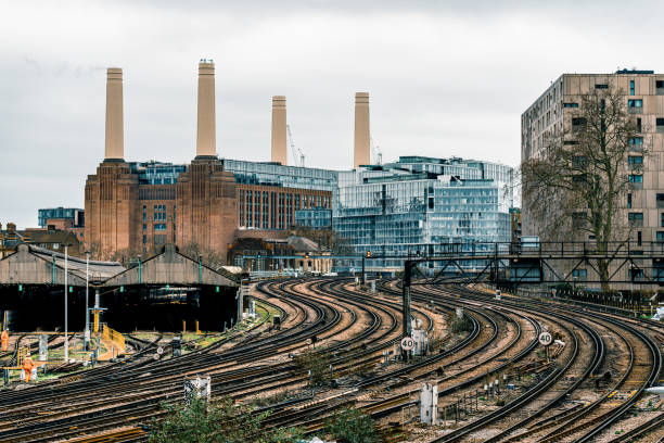 Battersea power station rail train Battersea Power Station the iconic decommissioned coal-fired power station located on the south bank of the River Thames in London. The Art Deco landmark surrounded by cranes during redevelopment building work - seen from Victoria Railway Station approach and shunting yard with approaching trains floodlight photos stock pictures, royalty-free photos & images