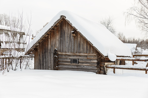 Wooden barn for animals. Log barn in the village in winter.