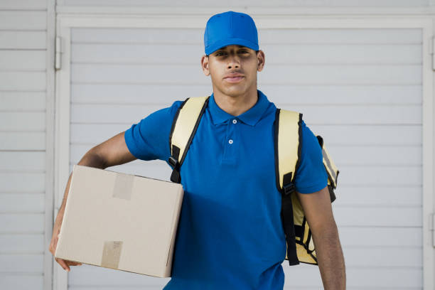 istock African delivery man holding box package for customer distribution - Focus on face 1367559273
