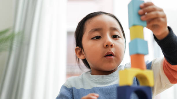 junges asiatisches kind, das zu hause mit farbblöcken spielt - kindergarten-lernspiele - fokus auf jungenmund - indian child stock-fotos und bilder