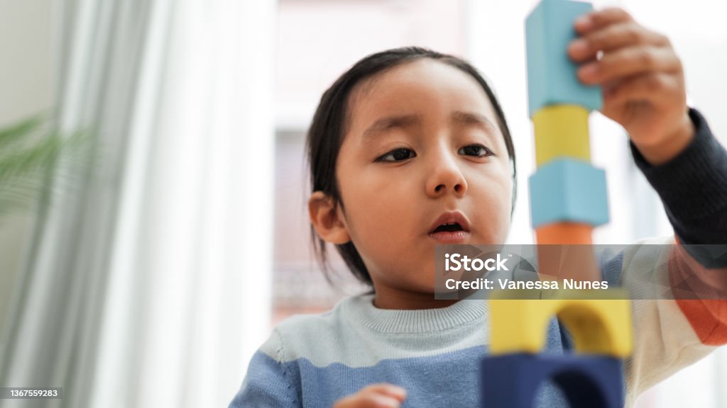 Young asian kid playing with color blocks at home - Kindergarten educational games - Focus on boy mouth Indigenous Peoples of the Americas Stock Photo