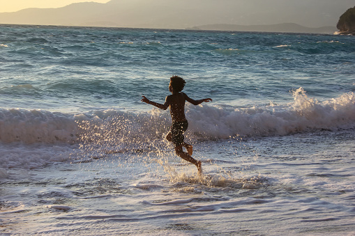 American boy frolics, bathes and swims in the sea. Plays in the spray of sea waves.