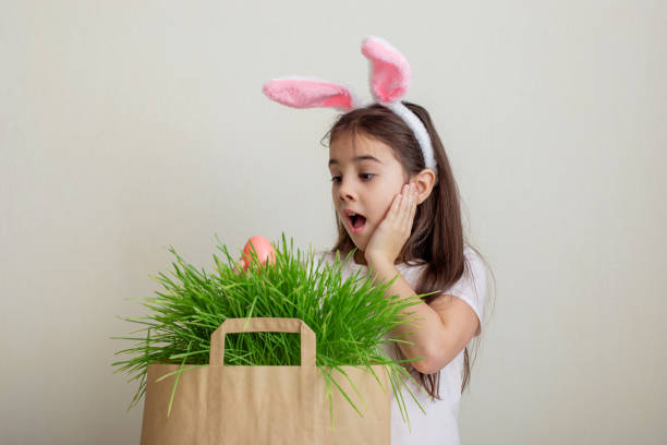 istock A little girl with hare ears, holds a pink egg 1367564272