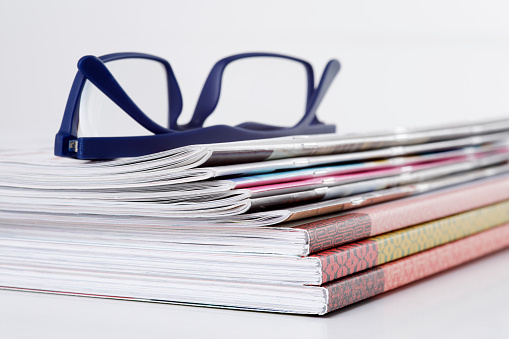Stack of magazines with reading glasses