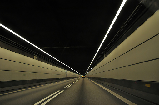 A highway in a deep underwater tunnel in Europe that connects Denmark and Sweden. Fast driving on the road in the tunnel.