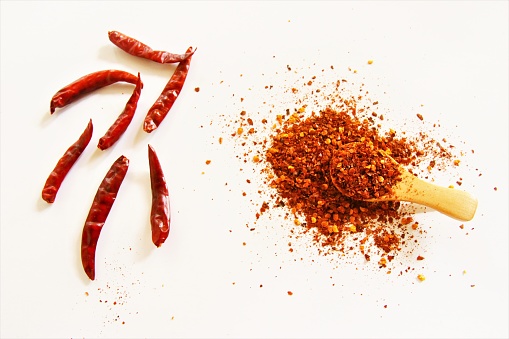 Dried chili pepper with wooden spoon of chili power photo isolate on white background  top view
